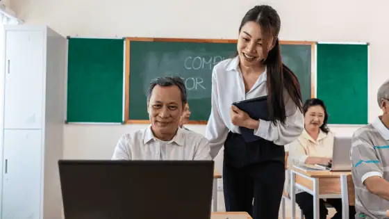 a female teacher supporting adult students in a classroom.