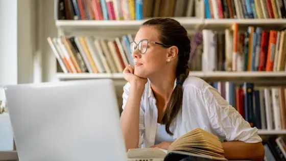 woman sat at her laptop in front of bookshelf