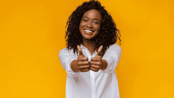 woman standing smiling and giving thumbs up with both hands