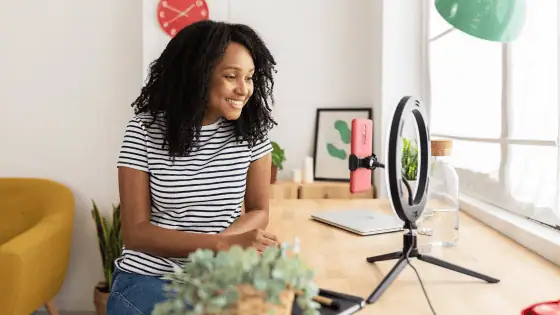 woman working as a content creator sat in front of phone and ring light